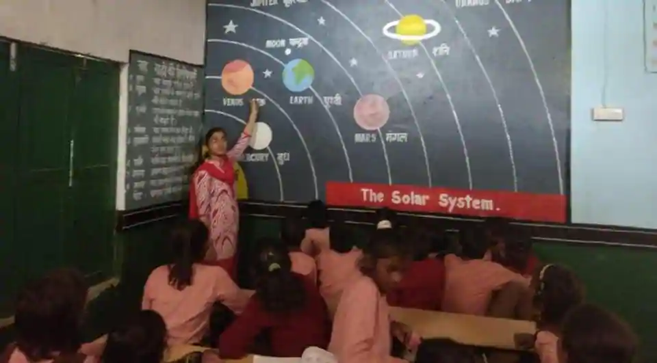 A teacher busy teaching students at a government-run primary school in Prayagraj.